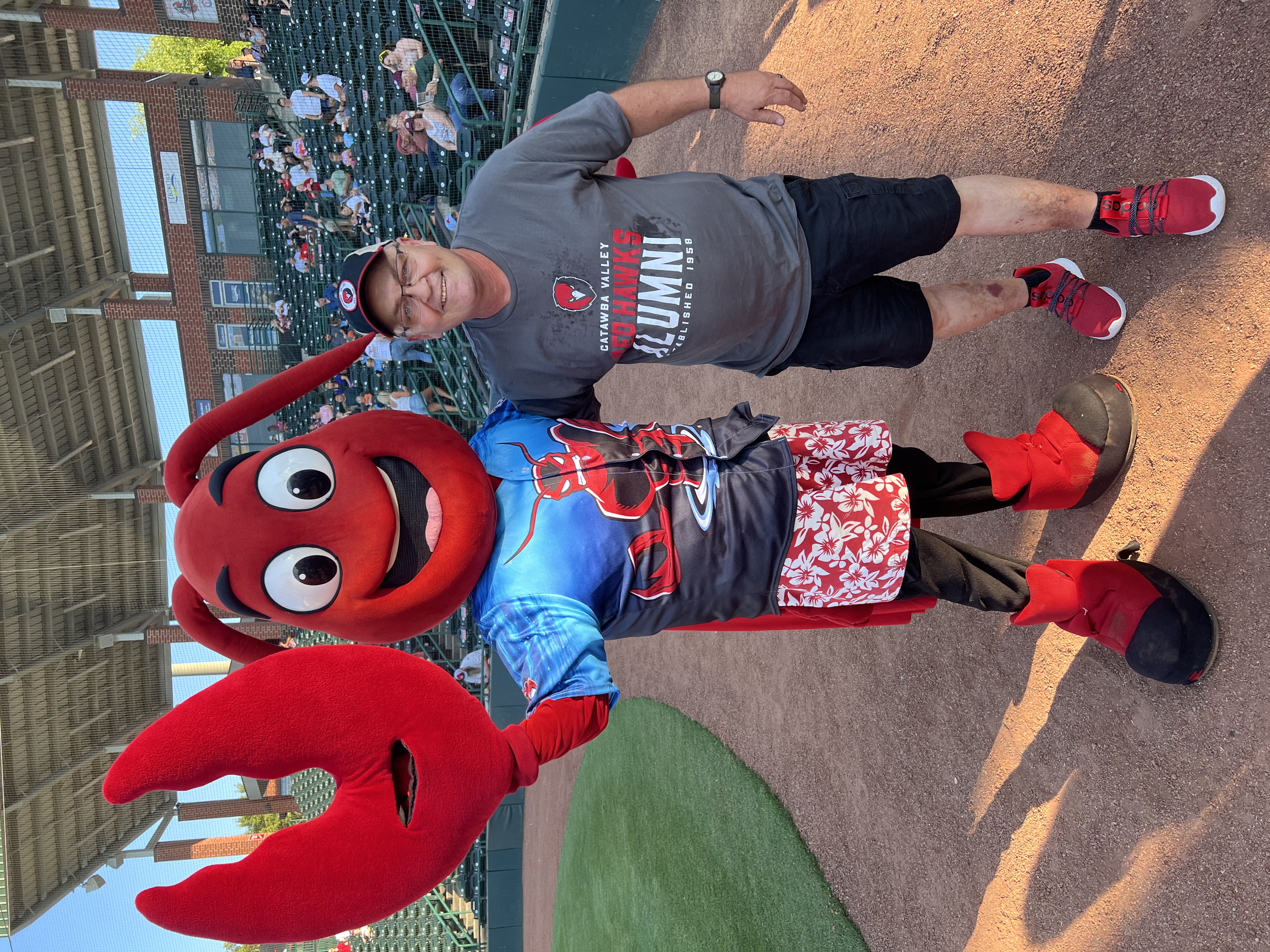 CVCC Alum Johnny Hull ('21) stands with Crawdad's Mascot after giving the first pitch.