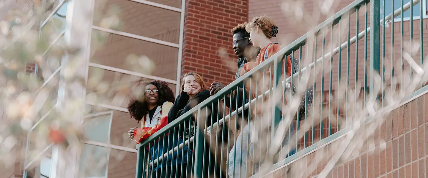 Group of students socializing on an upper-level outdoor balcony.
