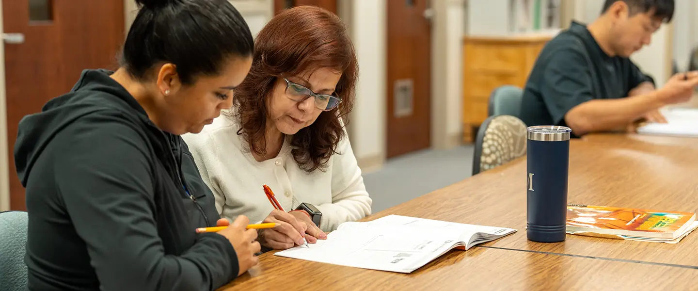 Adult learner working with instructor discussing coursework together.