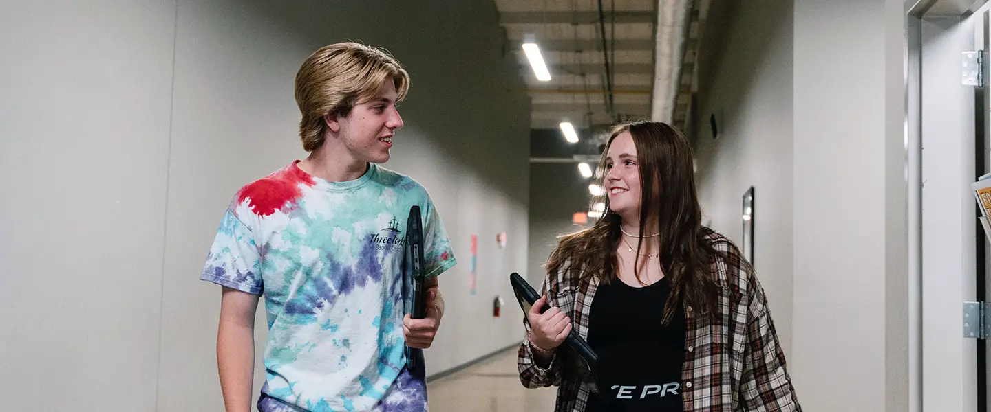 Students talking and walking together through a campus hallway.
