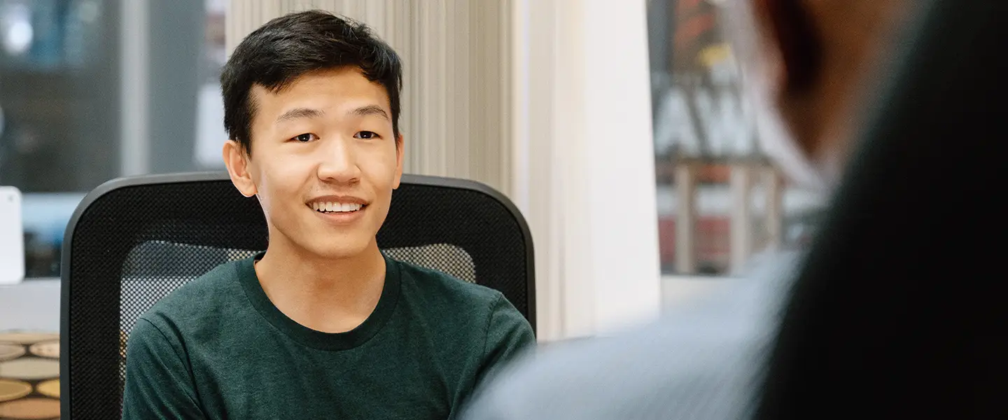 Student smiling during a discussion in an office setting.