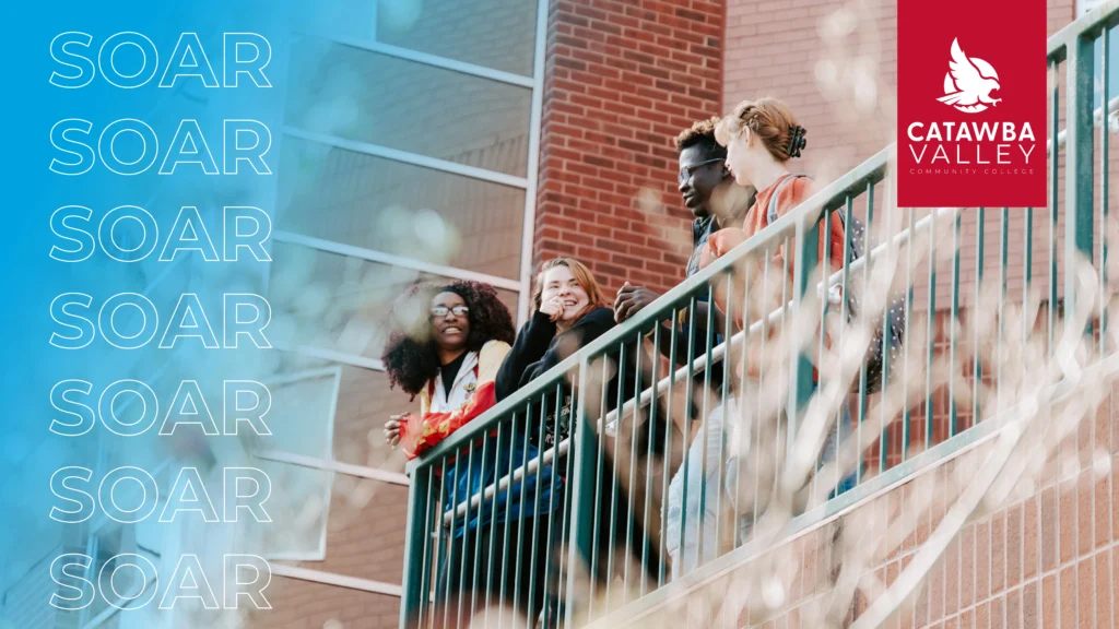 Promotional image for Catawba Valley Community College. On the left, the word “SOAR” is repeated vertically in white text against a blue gradient background. On the right, a group of four diverse students stands smiling on an outdoor stairway railing in front of a red brick building. The CVCC logo, featuring a white hawk on a red background, is placed in the top-right corner. Out-of-focus branches frame the bottom-right foreground.