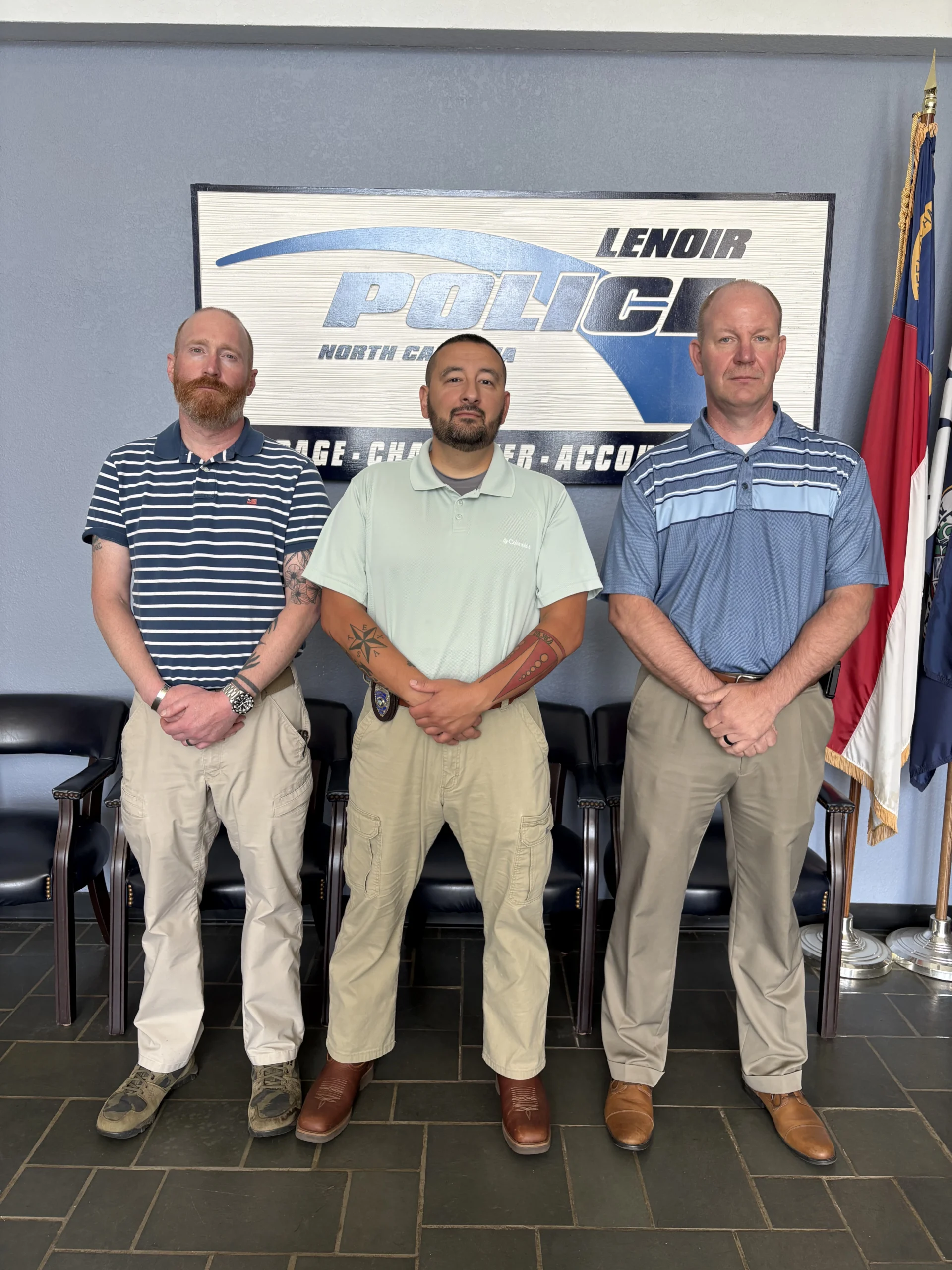 Three Lenoir Police officers who completed the Criminal Justice program stand side by side in front of a Lenoir Police sign. From left to right: John H., Brandon M., and Mark B.